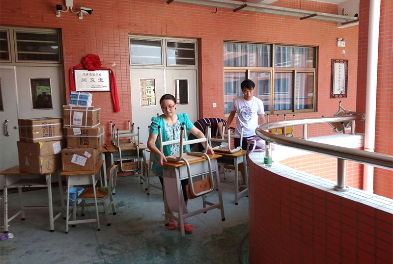 爱游戏官网志愿者及家长用消毒液擦拭桌椅